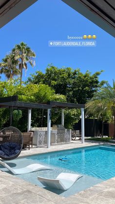 an empty pool in the middle of a backyard with lounge chairs and tables around it