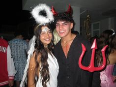 a man and woman pose for a photo at a party with devil horns on their head