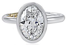 an oval shaped diamond ring with two tone gold accents on the band and side stones