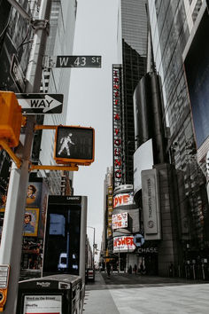 a city street filled with tall buildings next to traffic lights and pedestrians walking on the sidewalk