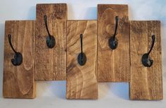 four wooden pieces with hooks on them are hanging from the wall, and one is made out of wood