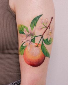 a woman's arm with an apple and flower tattoo on the left side of her arm