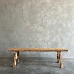 a wooden bench sitting in front of a wall with concrete floors and walls behind it