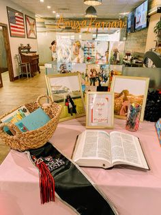 an open book sitting on top of a table next to two pictures and a basket