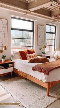 a large bed sitting in a bedroom next to two windows and a rug on the floor