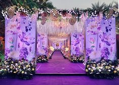 an outdoor wedding setup with purple flowers and chandeliers