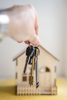 a hand holding keys to a small house