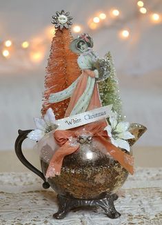 a small christmas tree sitting on top of a metal pot filled with snowflakes