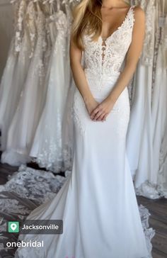 a woman standing in front of a rack of wedding dresses