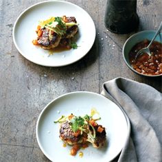 two white plates topped with meat covered in sauce