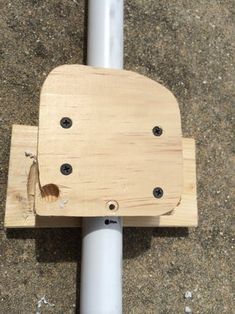 a piece of wood sitting on top of a metal pole next to a white pipe