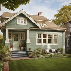 a blue house with white trim on the front door and windows, sitting next to a green lawn