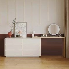 a white dresser sitting next to a mirror on top of a wooden floor