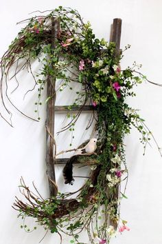 an old ladder is decorated with flowers and greenery to look like it has been made into a wreath