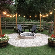 an outdoor fire pit surrounded by wooden posts and chairs with lights strung over the top