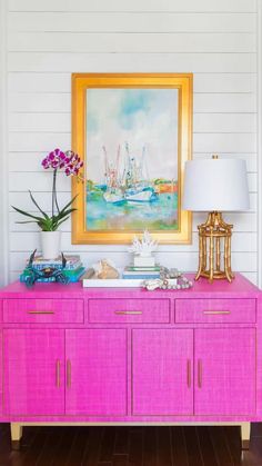 a pink sideboard in a white room with a painting on the wall behind it