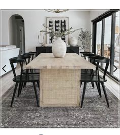 a dining room table with black chairs and a white vase on it's centerpiece