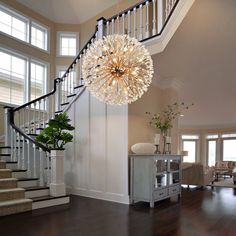 a large chandelier hanging from the side of a stair case in a living room