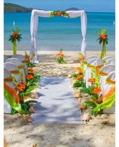 an outdoor wedding set up on the beach with flowers and greenery at the end