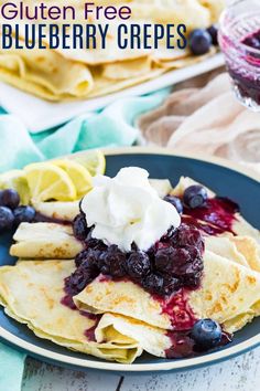 blueberry crepes with whipped cream and lemon wedges on a black plate