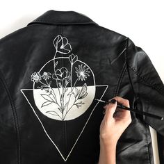 a person drawing flowers on a black leather jacket