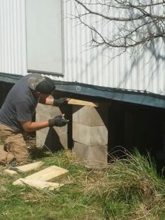 a man is working on some kind of structure in the grass near a building that has been built