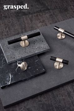 two black and gold cufflinks sitting on top of a marble slab with metal handles