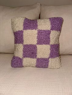 a purple and white pillow sitting on top of a bed