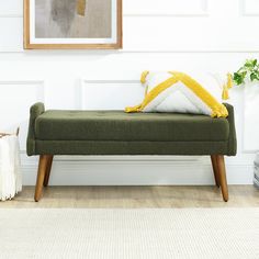 a green bench sitting in front of a white wall with a yellow and white pillow on it