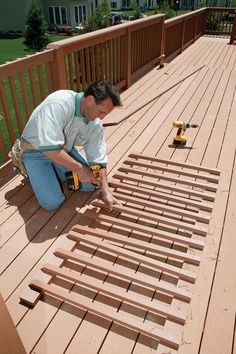 a man kneeling down on a deck working with wood planks and glue gunes