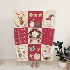 a woman standing in front of a christmas themed blanket