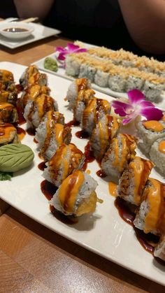 sushi is served on a white plate with sauce and garnishes around it