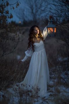 a woman in a white dress holding a lantern