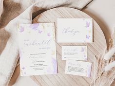 the wedding stationery is laid out on a wooden plate