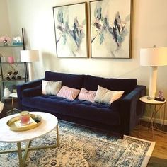 a living room with two paintings on the wall and a blue couch in front of it