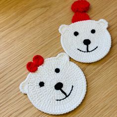 two crocheted polar bear coasters sitting on top of a wooden table