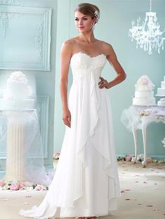 a woman in a white wedding dress standing next to a table with flowers on it