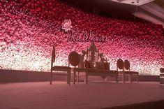 an artistic display with red flowers on the wall and benches in front of it,