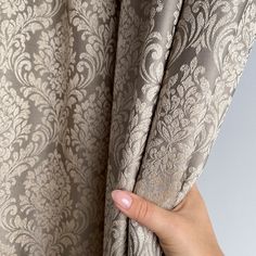 a hand is opening the curtain to reveal an intricate pattern