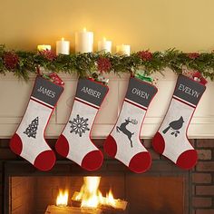 three stockings hanging from a mantel over a fire place with candles in the background