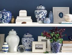 an image of a shelf with vases and books on it's shelves in front of a blue wall