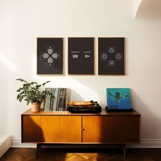 a record player sitting on top of a wooden cabinet next to two framed pictures above it