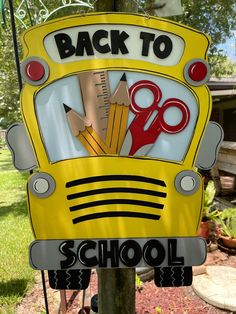 a yellow school bus with scissors and pencils on it's back to school sign