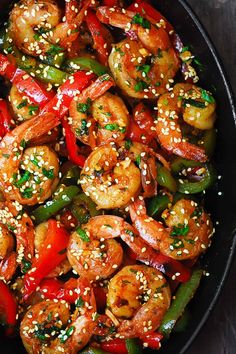 a skillet filled with shrimp, peppers and sesame seeds