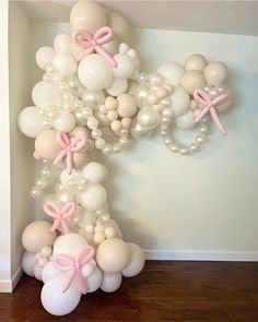 balloons and bows are arranged in the shape of an x on a wall with wood flooring