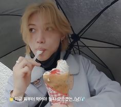 a woman is holding an umbrella and eating ice cream