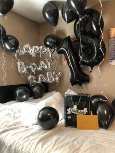 a bed with black balloons and a happy baby sign