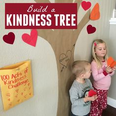 two children standing in front of a tree with hearts on it and the words build a kindness tree