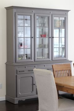 a dining room table and chairs in front of a gray china cabinet with glass doors