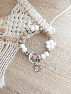 a white bracelet with beads and a silver clasp on a wooden table next to a crocheted bag